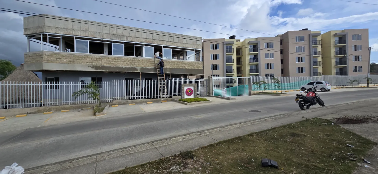 Edificio de zonas comunes de Jardines en estructura, con bloques de apartamentos terminados al fondo.