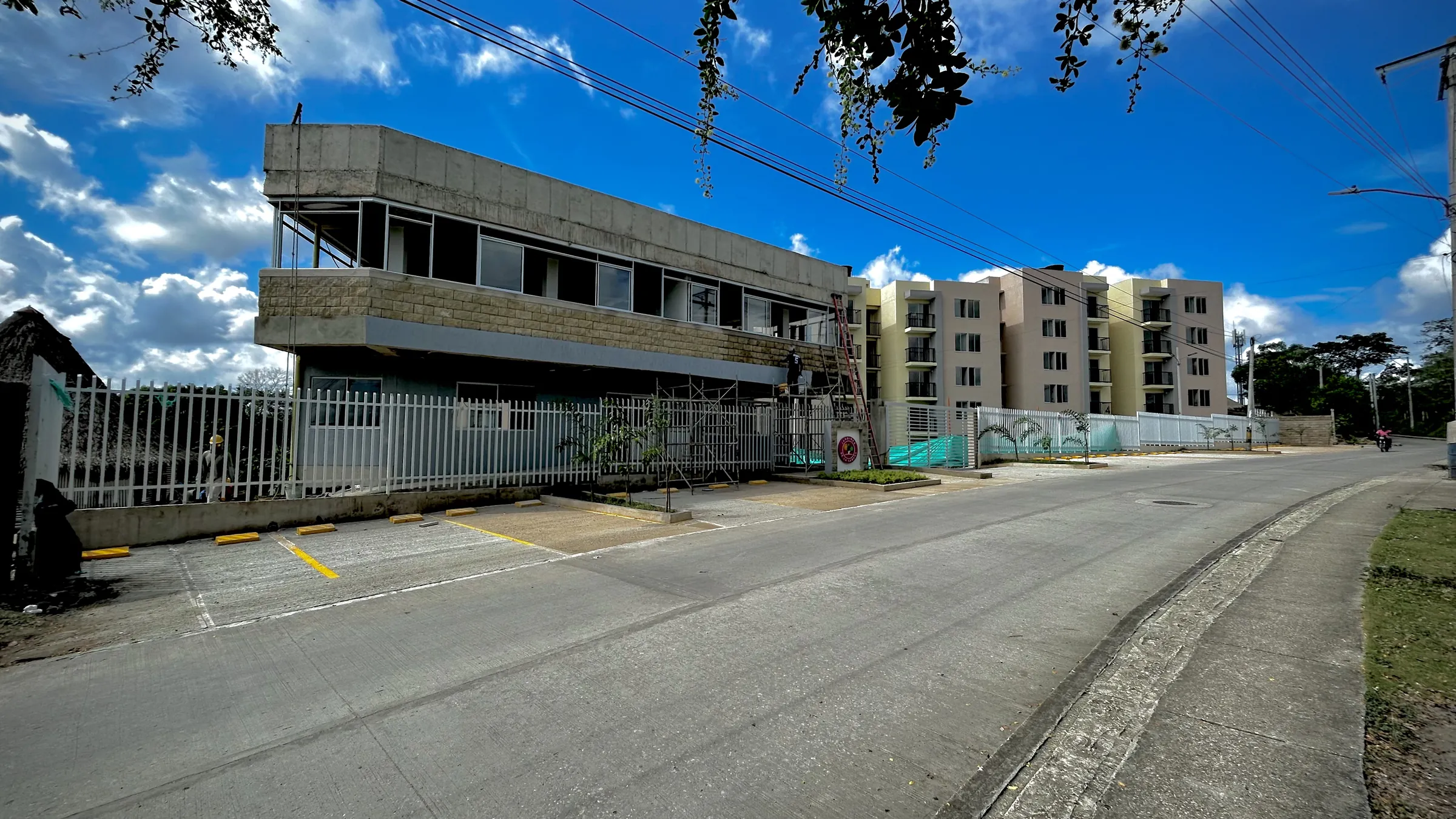 Edificio de zonas comunes de Jardines en obra, con bloques de apartamentos al fondo.
