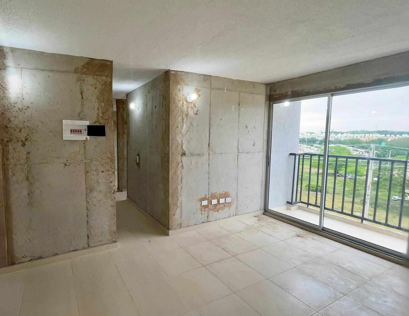 Sala de Jardines con piso instalado, paredes sin acabado y puerta corrediza al balcón.